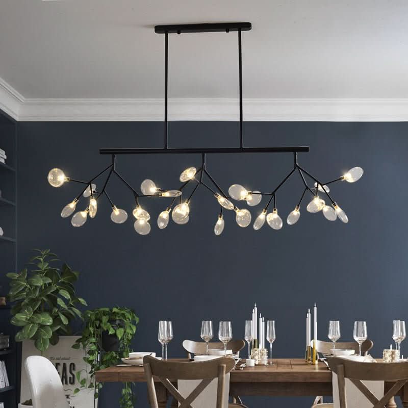 Lustre noir suspendu devant un mur bleu foncé, table de salle à manger dressée.