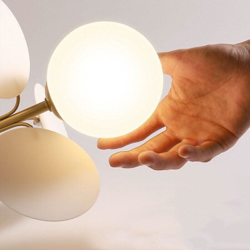 Détail en gros plan d'une main tenant un globe de verre opalin et un disque pastel.