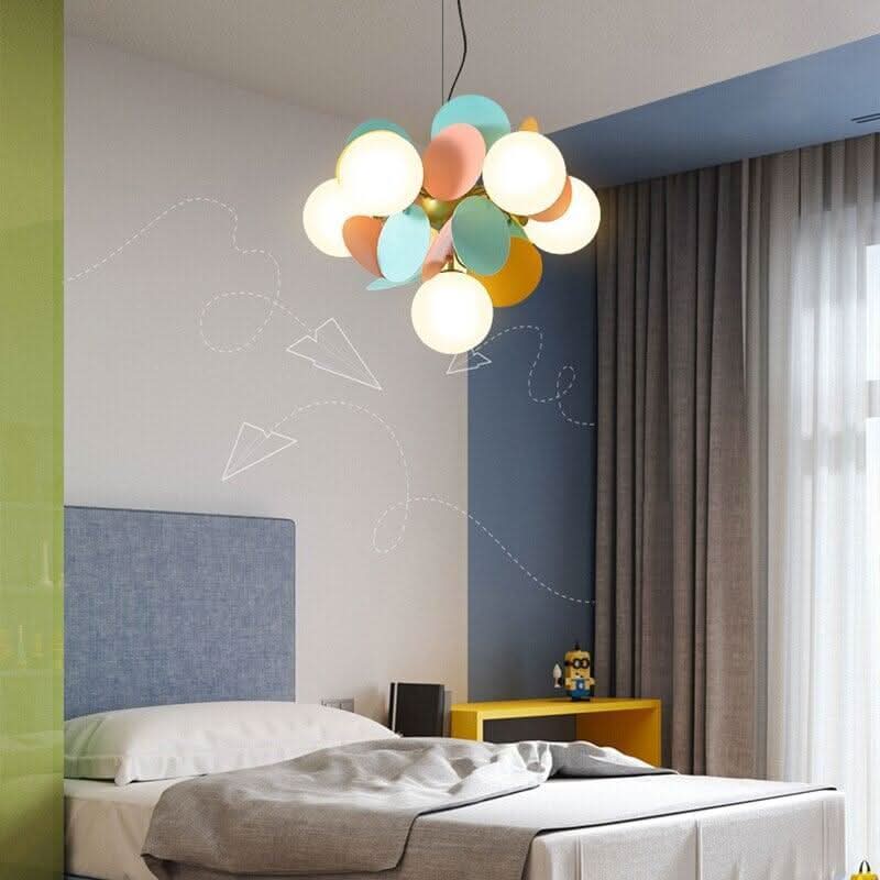 Suspension colorée éclairant une chambre, au-dessus d'un lit avec mur bleu et dessins.
