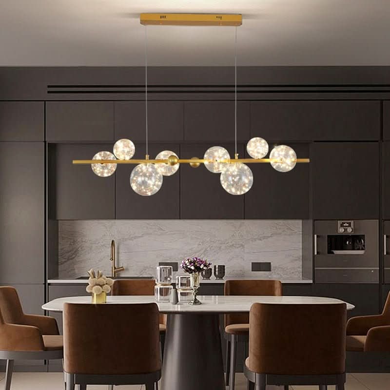 Luminaire doré suspendu dans une cuisine moderne, crédence marbre et chaises marron