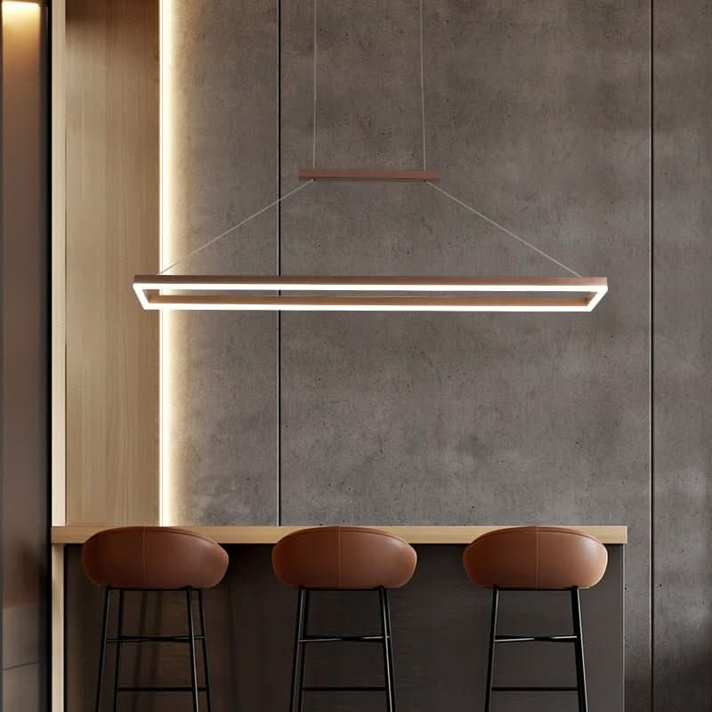 Mur en béton brut, trois tabourets en cuir et suspension rectangulaire en bois au-dessus du comptoir.