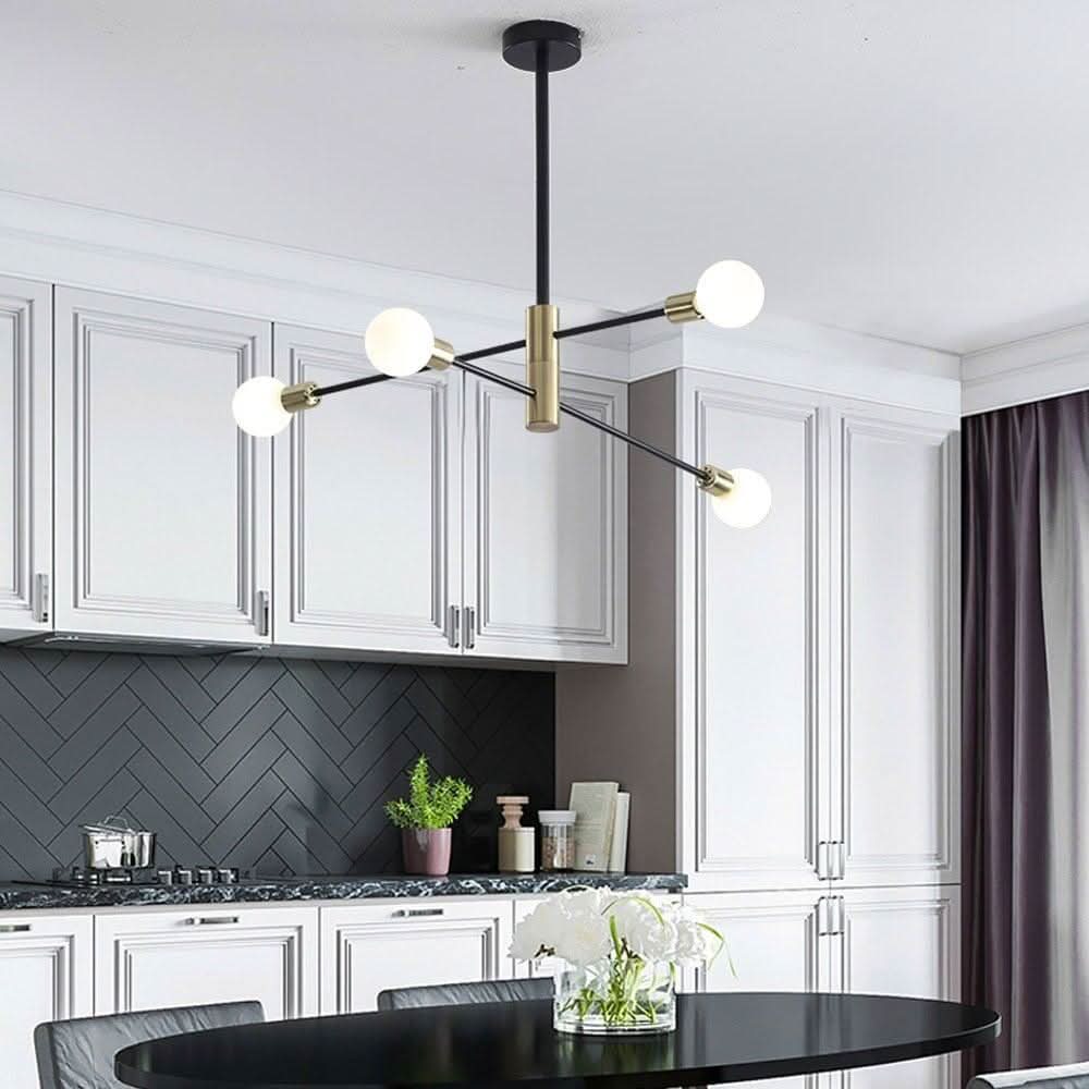 Lustre suspendu au-dessus d'une table de cuisine, quatre globes blancs, tige noire et détails dorés.