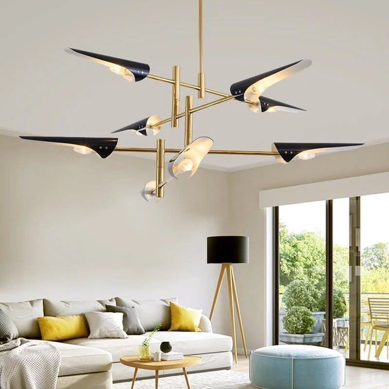 Suspension moderne aux abat-jours noirs et bras dorés dans un séjour lumineux avec canapé beige.