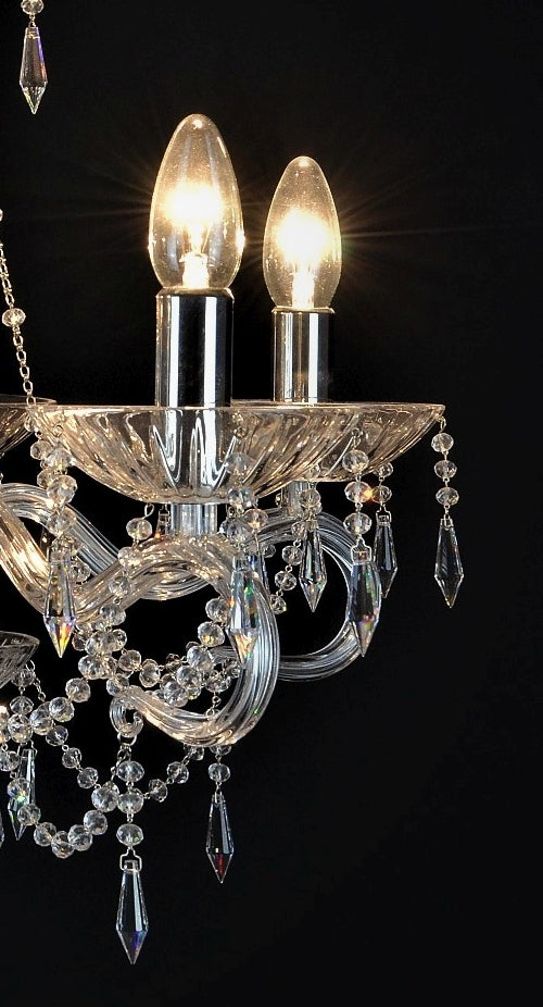 Gros plan sur deux ampoules flamme allumées, coupelles festonnées et pendeloques de cristal taillé