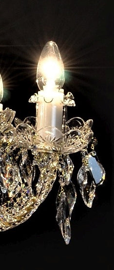 Gros plan sur une douille blanche, ampoule allumée et pendentif cristal taillé