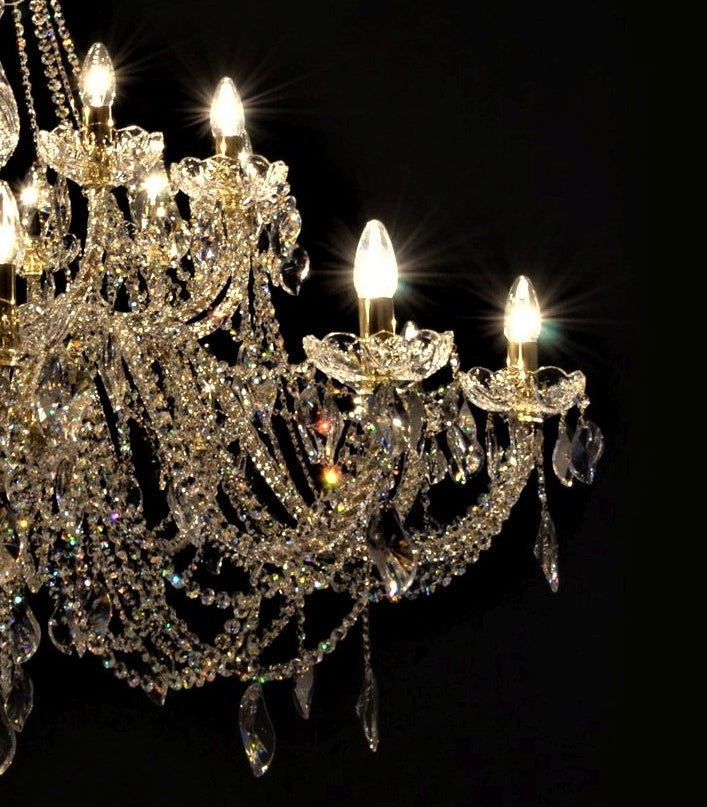 Détail des bras du lustre, cristaux taillés et ampoules allumées en gros plan.