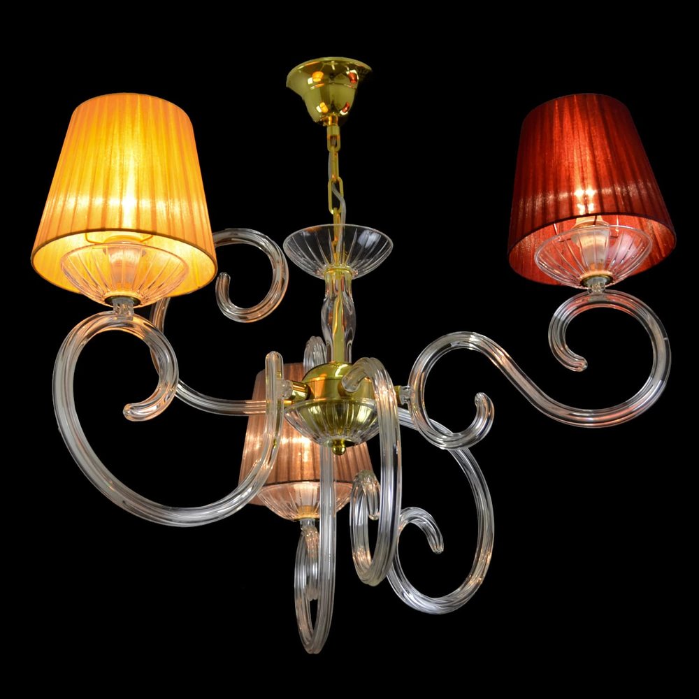 Même lustre allumé, abat-jours jaune et rouge diffusant une lumière chaude, fond noir.