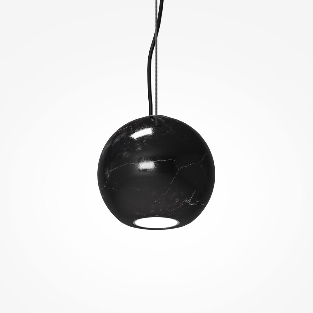 Gros plan sur la sphère en marbre noir et son ouverture lumineuse.