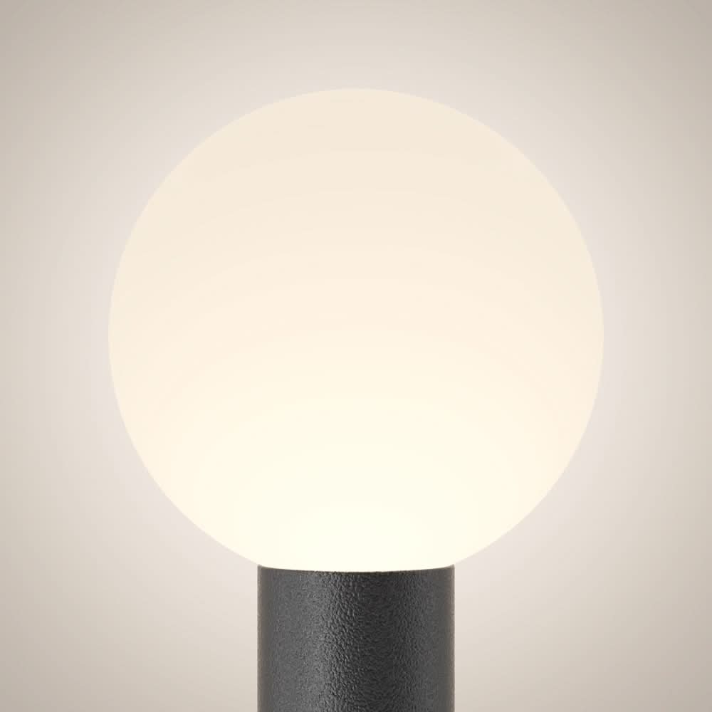 Gros plan du globe laiteux posé sur le fût cylindrique noir texturé