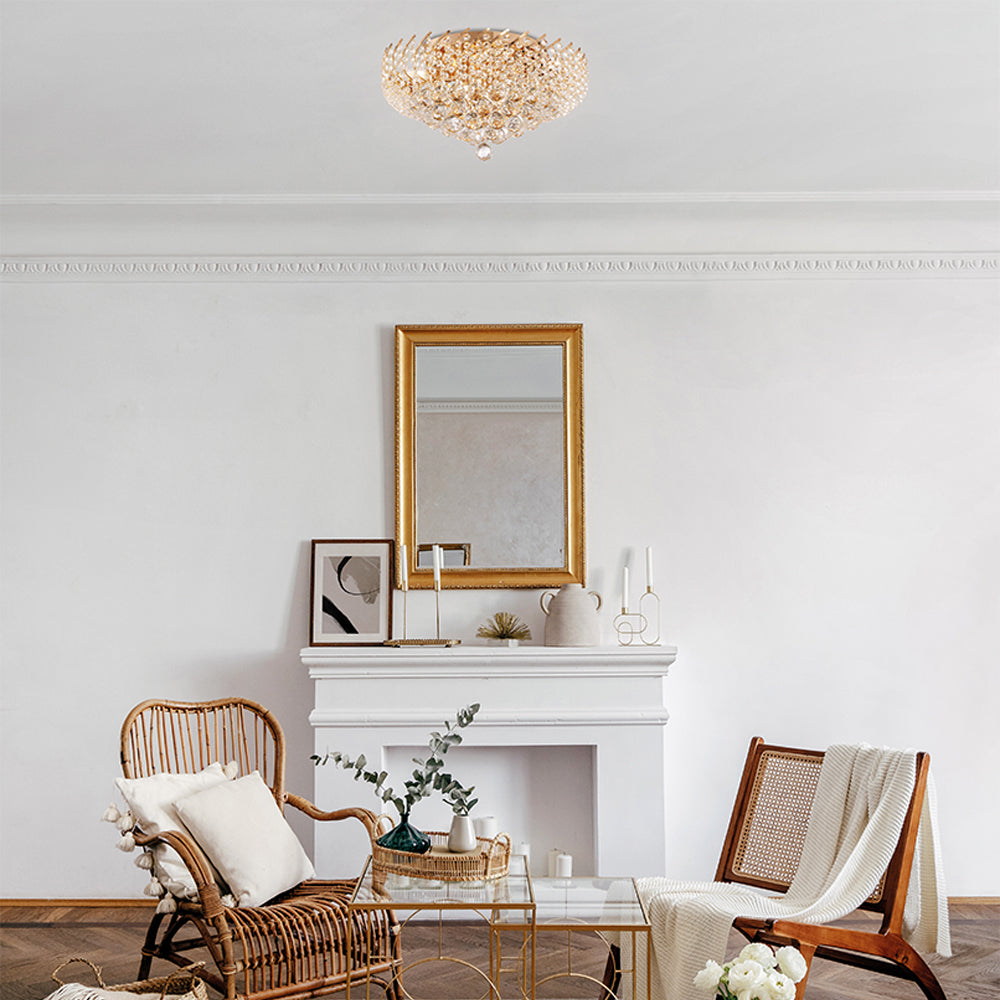 Plafonnier doré installé au plafond d'un salon blanc avec fauteuils en rotin