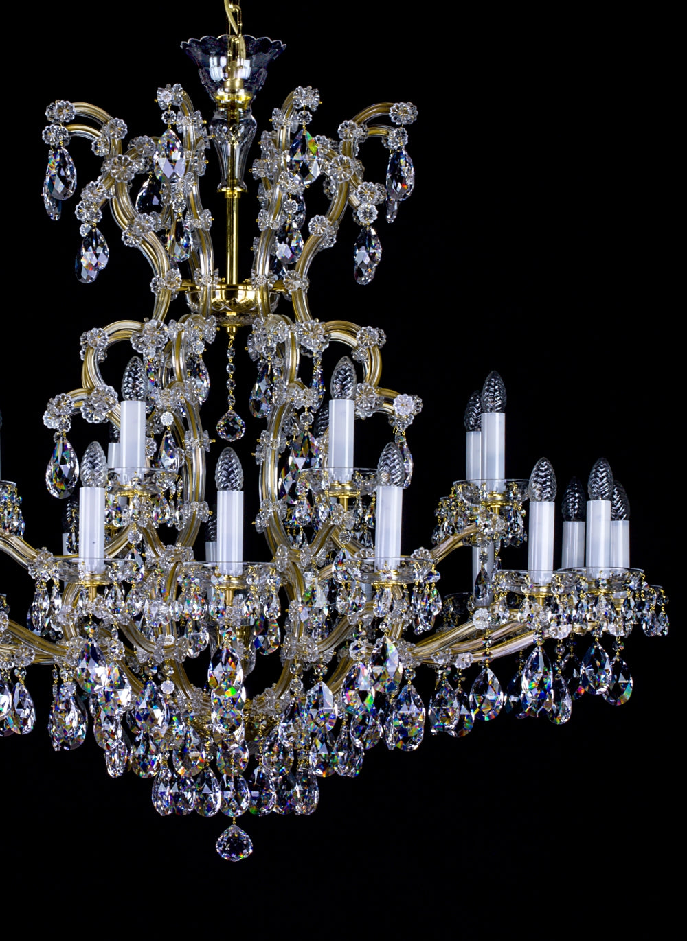 Détail du haut du lustre doré, avec bras recourbés, fleurs de cristal et pampilles.