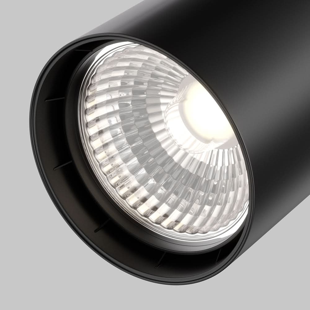 Gros plan sur la lentille striée et l'ampoule LED allumée du spot noir.