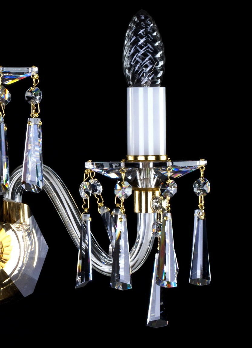 Détail d'un bras lumineux avec manchon blanc, bobeche de cristal et pampilles pendantes.