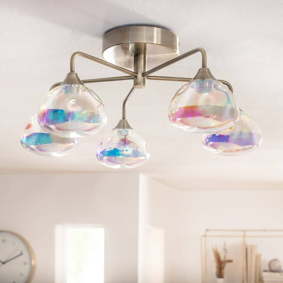 Vue rapprochée du plafonnier allumé, cinq globes irisés suspendus sous le plafond