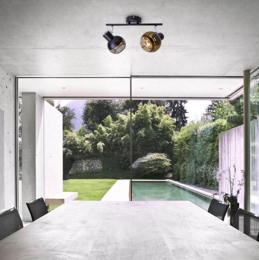 Plafonnier installé au plafond au-dessus d'une table, ouverture sur un jardin et piscine.