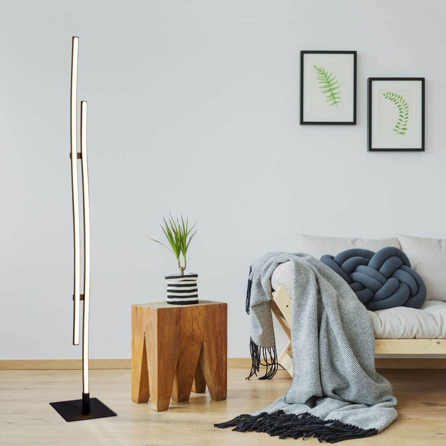 Lampadaire allumé dans un salon déco avec table en bois et plante verte