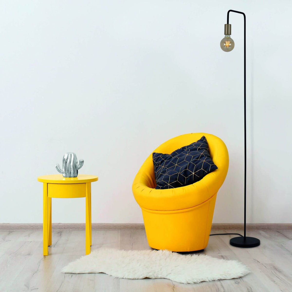 Mise en ambiance salon avec fauteuil jaune, table jaune et lampadaire allumé.