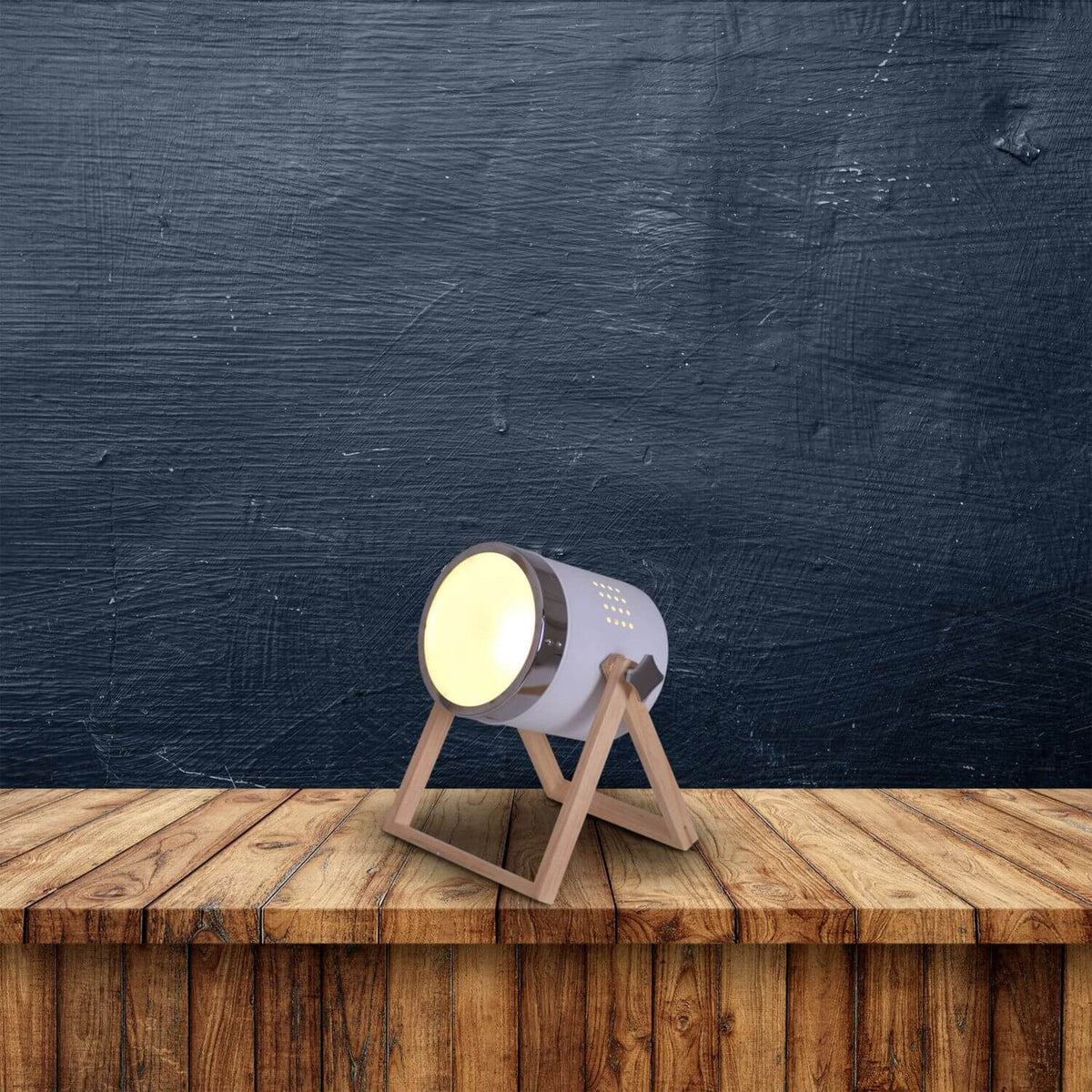 Lampe allumée posée sur une table en bois devant un mur sombre texturé
