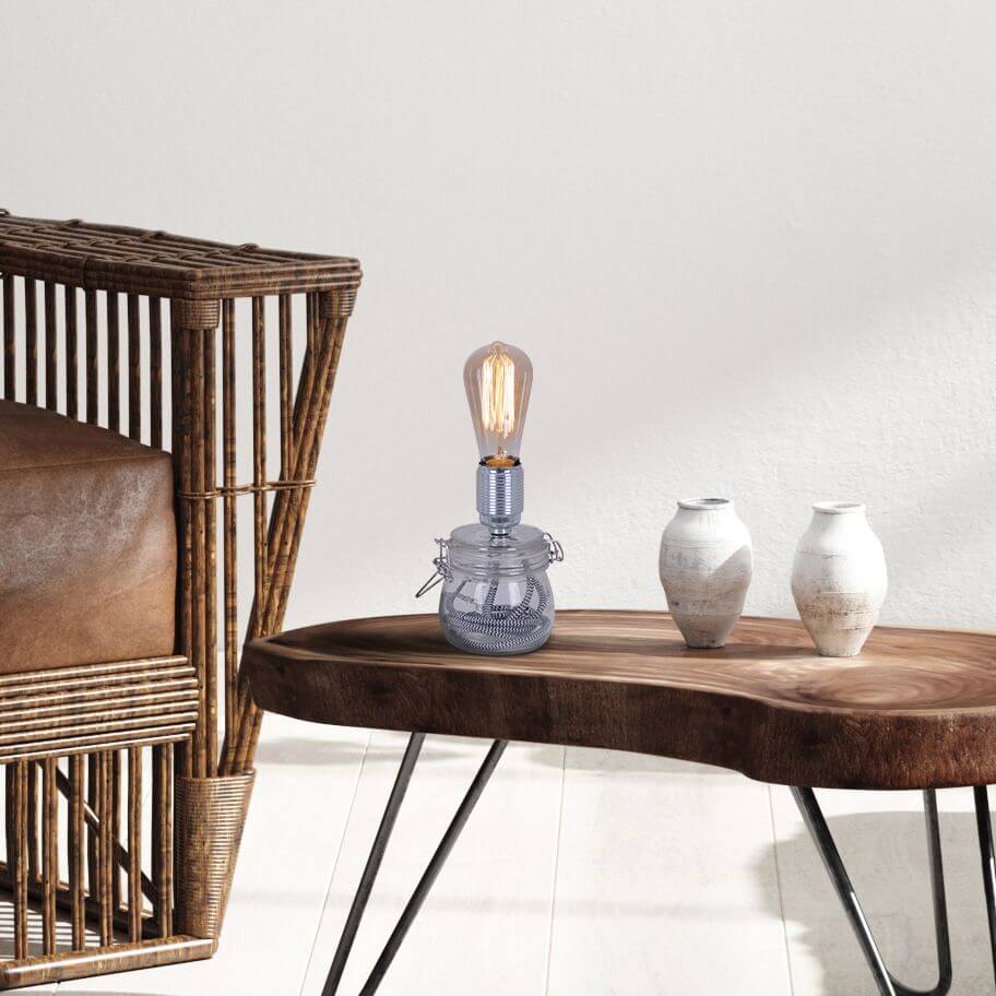Lampe allumée sur une console en bois, près d'un fauteuil en rotin et de vases