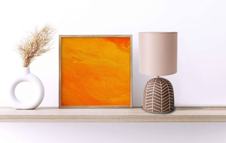 Lampe posée sur une étagère près d'un cadre orange et d'un vase