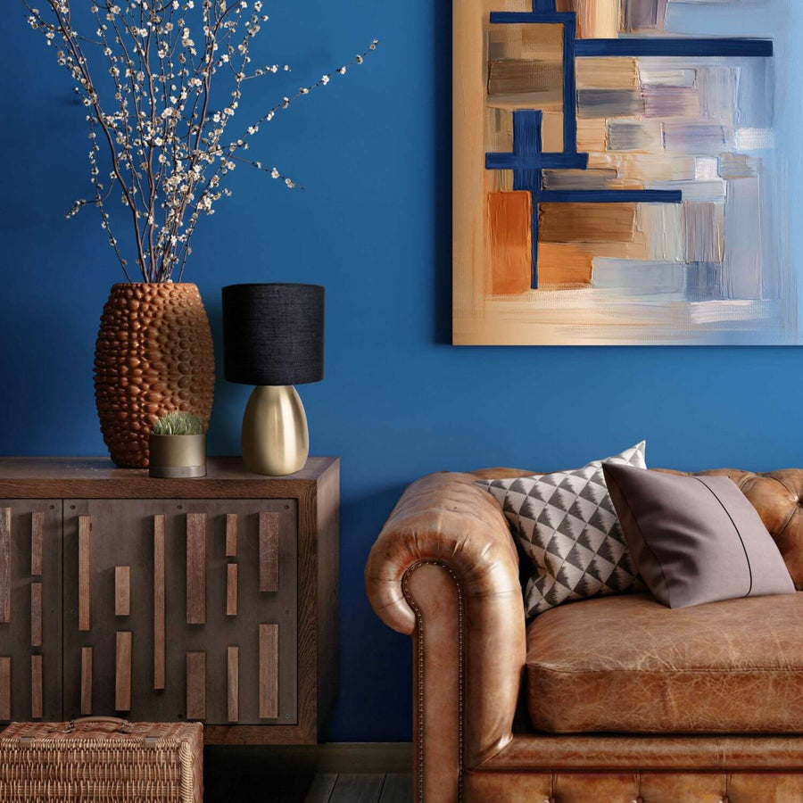 Lampe dorée sur buffet en bois, devant mur bleu et canapé en cuir.