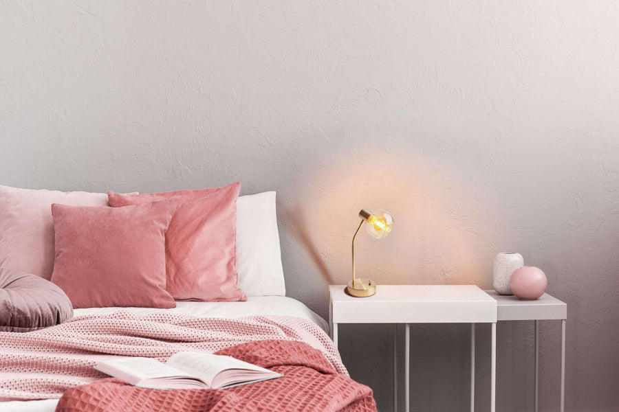 Lampe allumée sur une table de chevet blanche, diffusant une lumière chaude dans la chambre