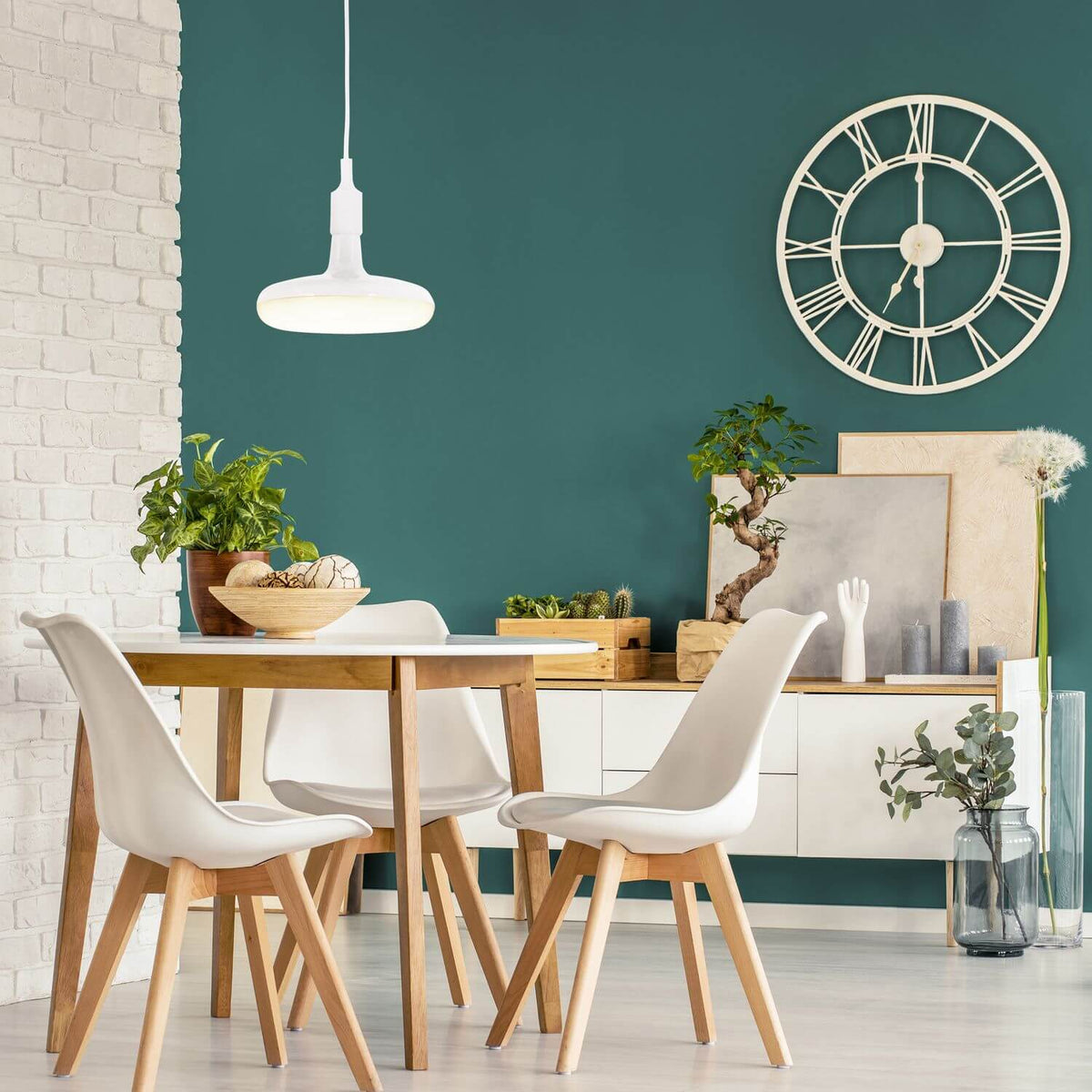 Suspension blanche allumée dans une salle à manger, mur vert bouteille et horloge murale