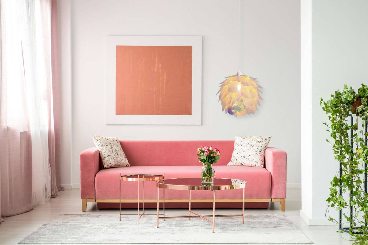 Suspension suspendue au-dessus d'un canapé rose devant un grand tableau orange.