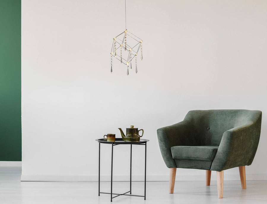 Luminaire suspendu au-dessus d'une table d'appoint dans un intérieur vert et blanc
