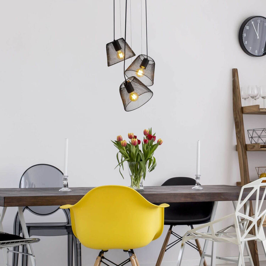 Luminaire suspendu allumé au-dessus d'une table de salle à manger avec chaise jaune.