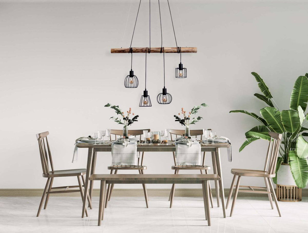 Suspension en bois flotté avec quatre cages métalliques noires, installée au-dessus d'une table à manger.