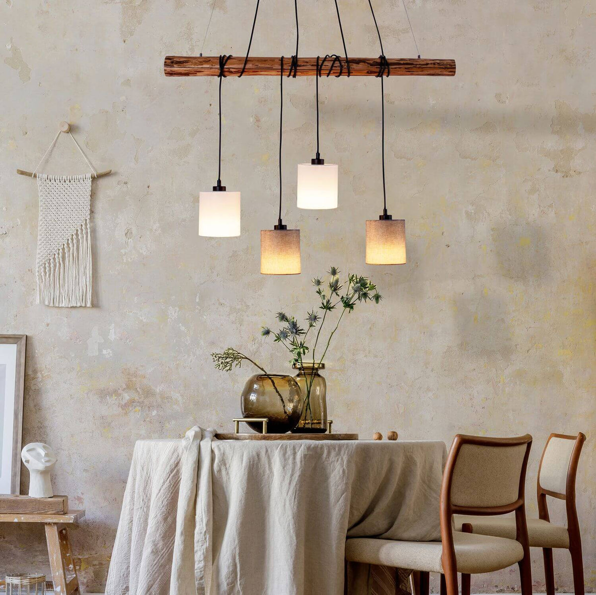 Suspension allumée au-dessus d'une table rustique dans un intérieur bohème