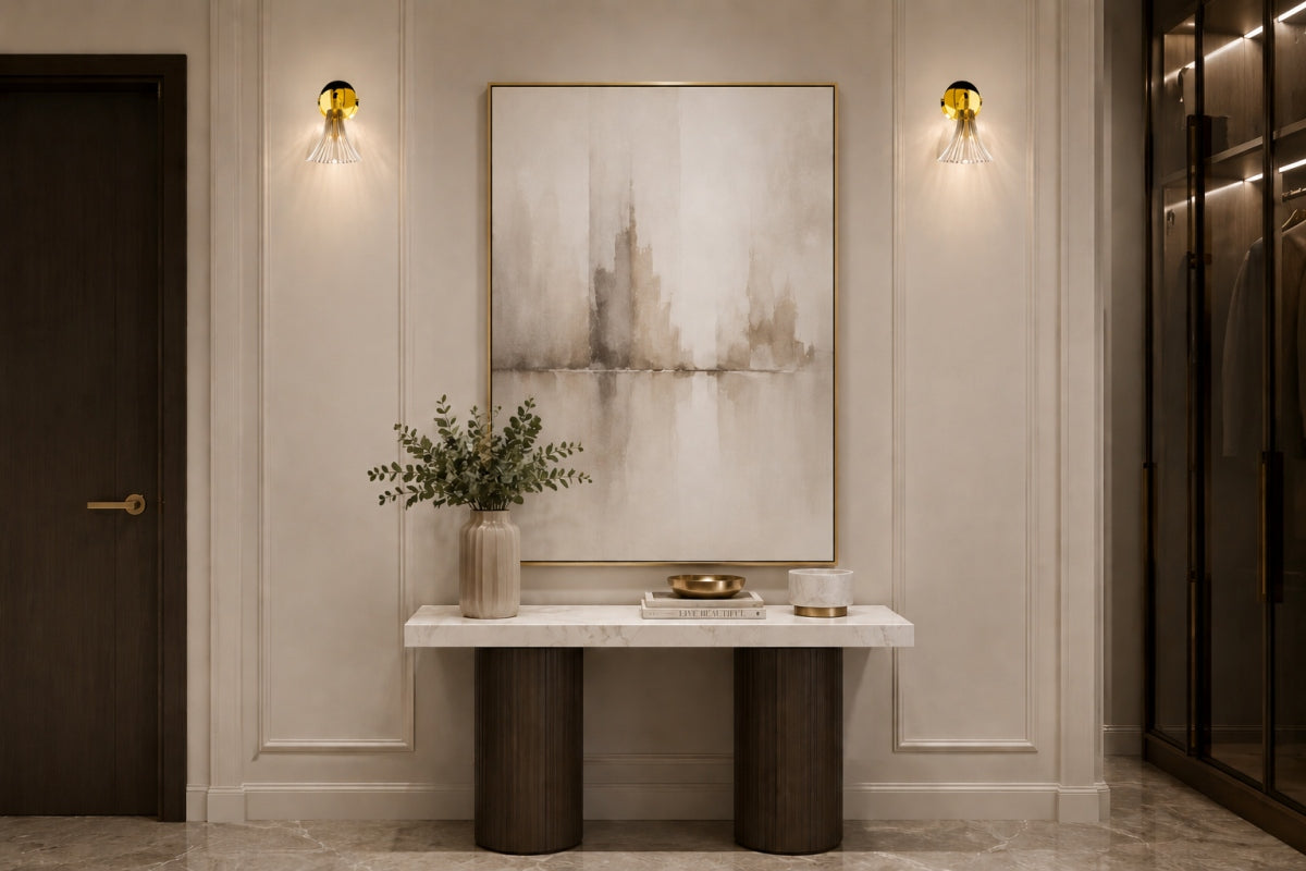 Entrée chic avec deux appliques dorées de part et d'autre d'un tableau, au-dessus d'une console.
