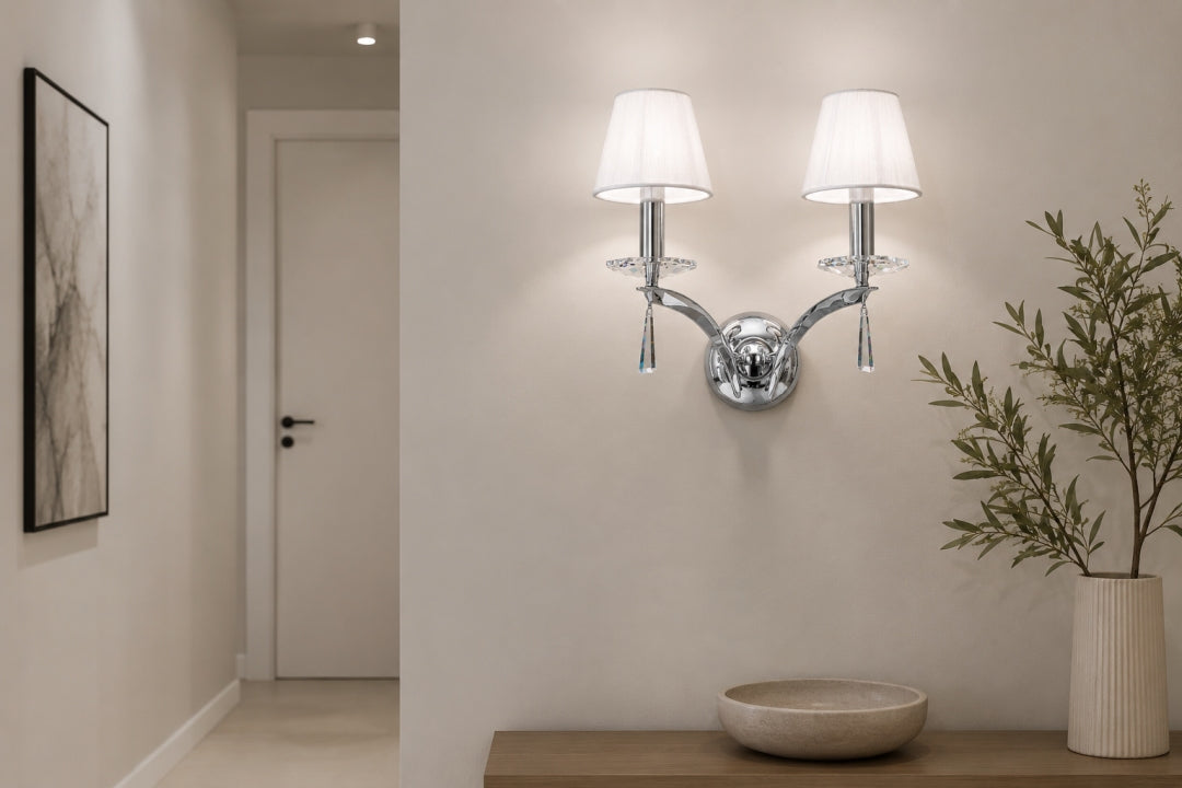 Vue dans un couloir clair, applique chromée éclairée près d'une plante en pot.