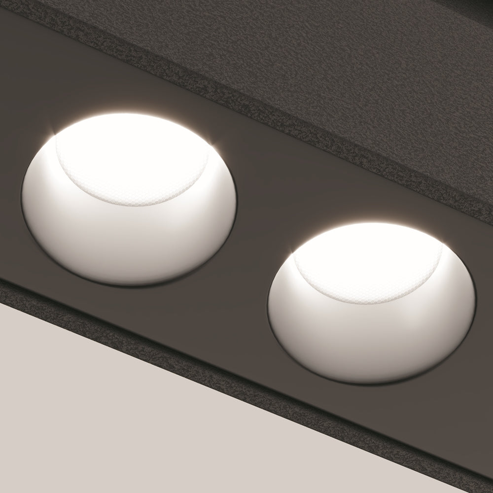 Détail rapproché de deux spots ronds allumés, halo lumineux sur rail noir.