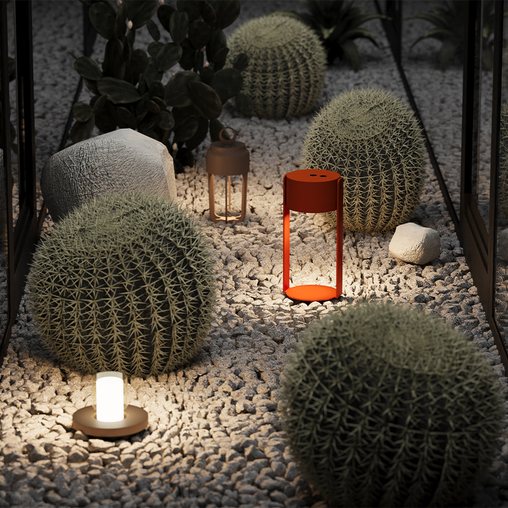 Mise en ambiance nocturne, petite lampe posée sur des graviers entre cactus et pierres