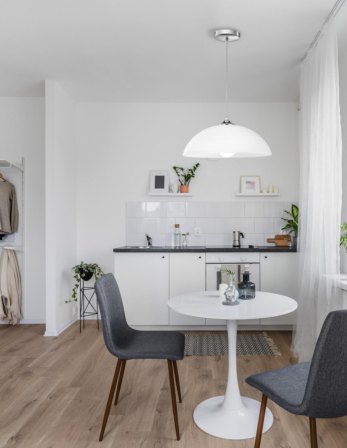 Mise en ambiance au-dessus d'une table ronde dans une cuisine blanche et bois clair.