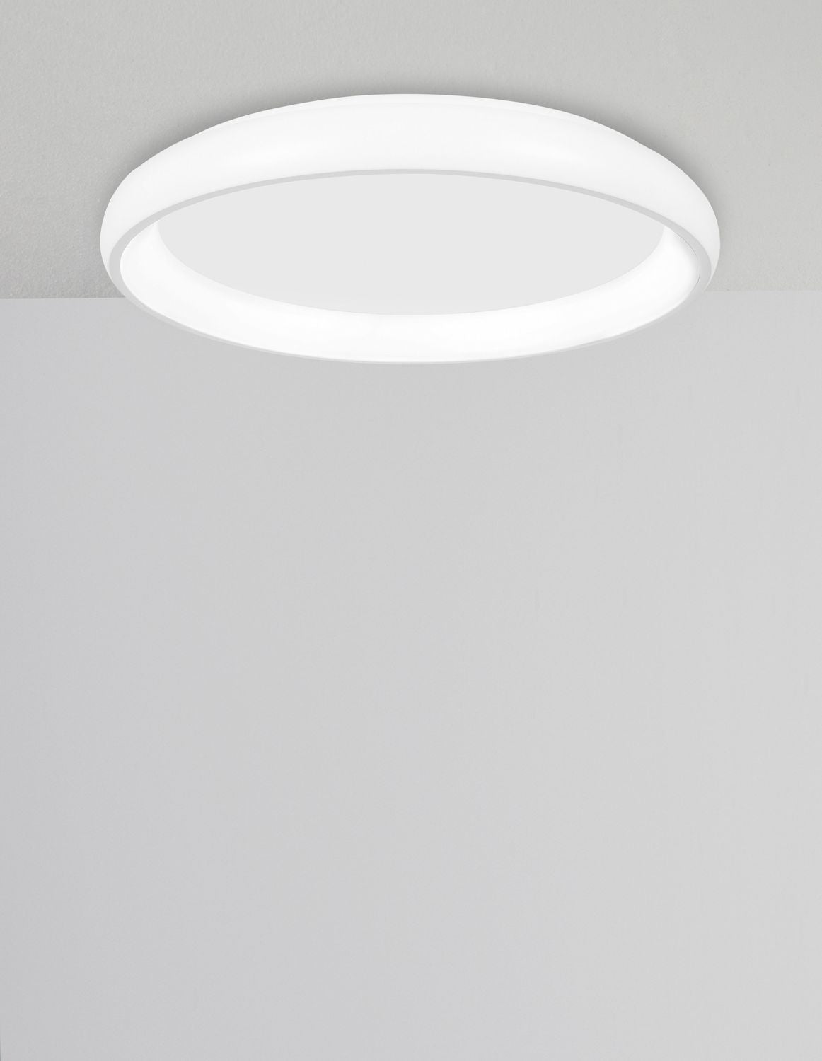 Plafonnier rond blanc allumé au plafond dans une pièce claire et épurée