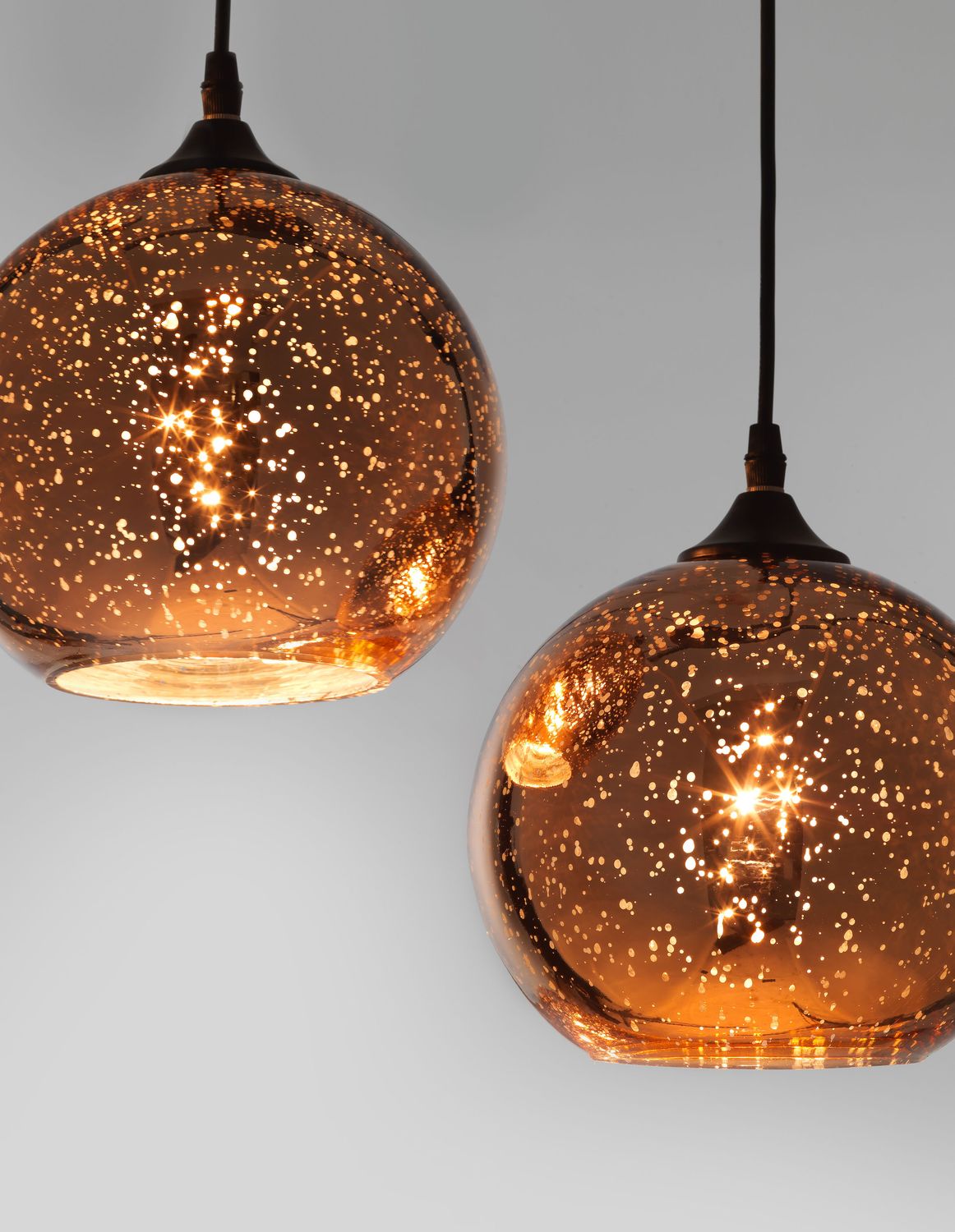 Détail rapproché des deux globes en verre moucheté et lumière chaude.
