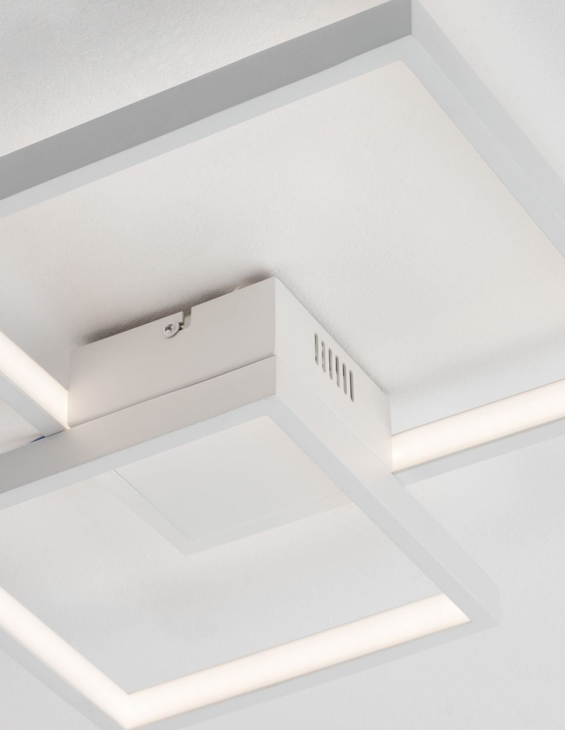 Détail du boîtier central blanc avec vis de fixation et fentes d'aération