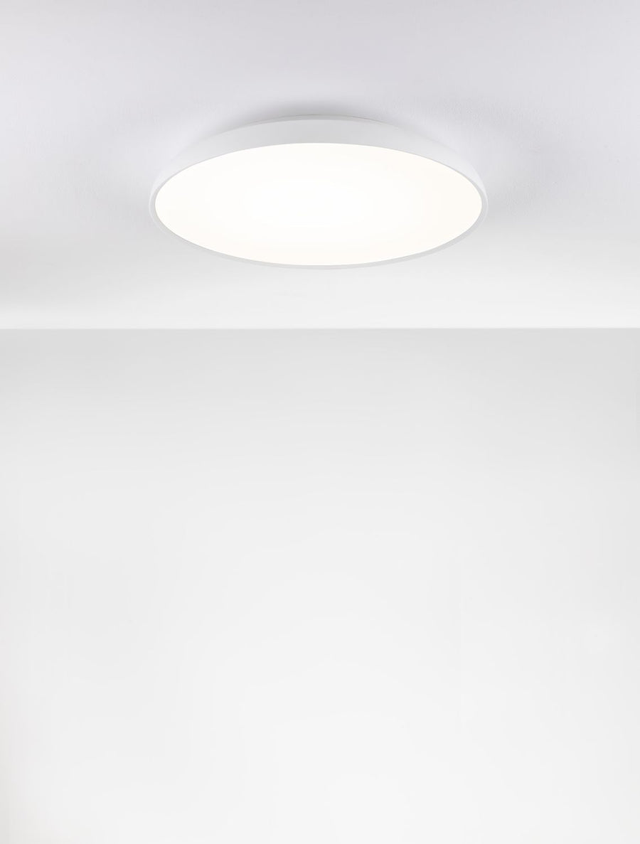 Plafonnier rond blanc allumé, fixé au plafond, lumière diffuse uniforme