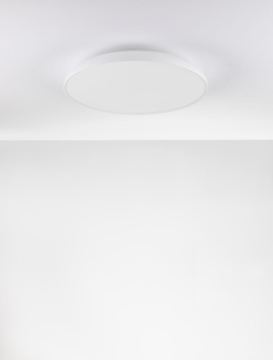 Mise en ambiance d'un plafonnier blanc installé, halo lumineux dans pièce claire