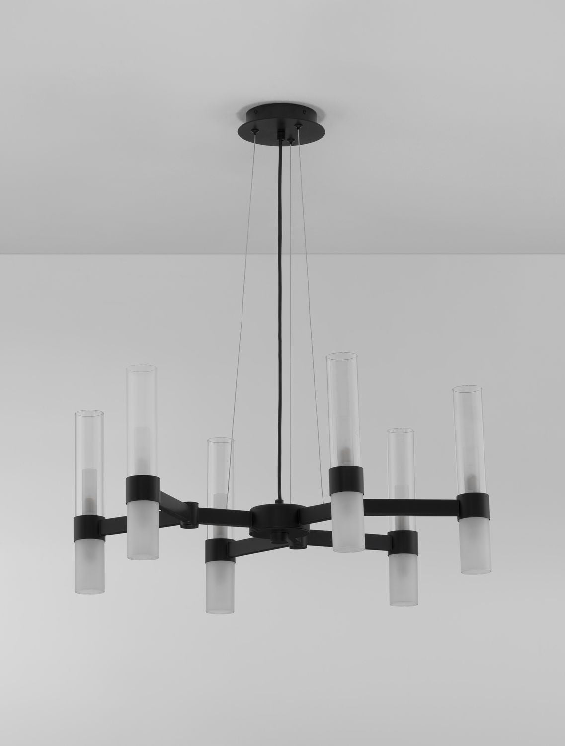 Détail du luminaire suspendu montrant la structure noire et les cylindres en verre dépoli.
