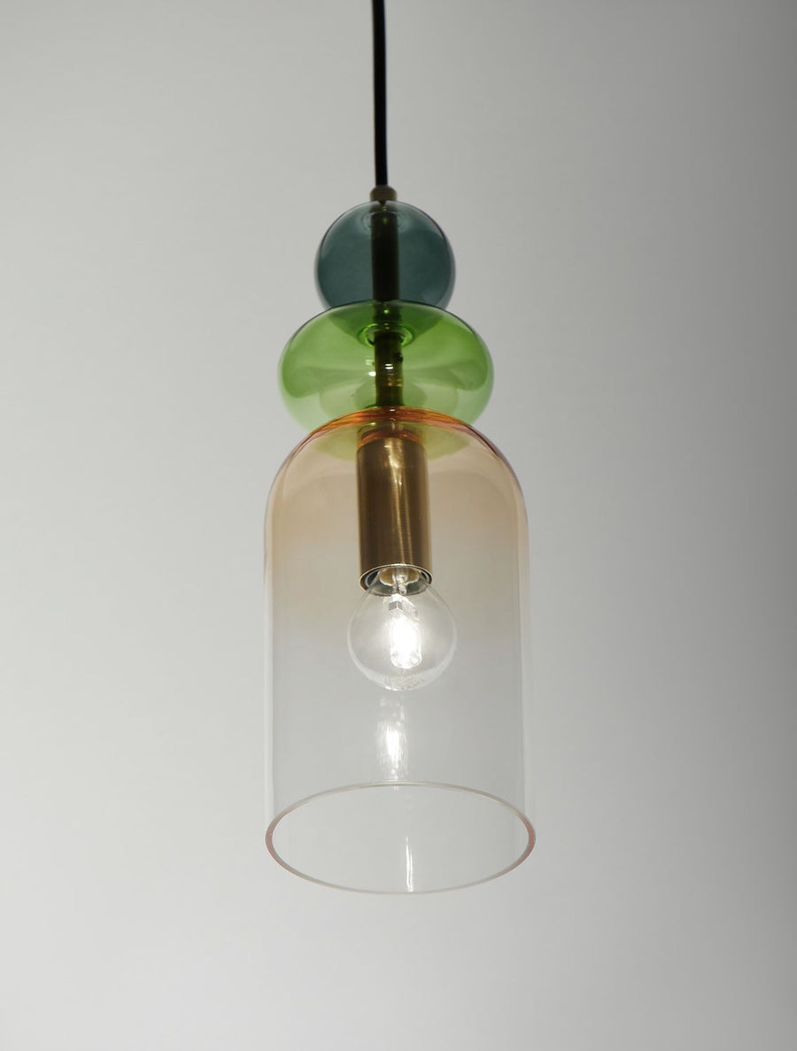 Gros plan sur la cloche en verre ambré, la douille dorée et l'ampoule allumée