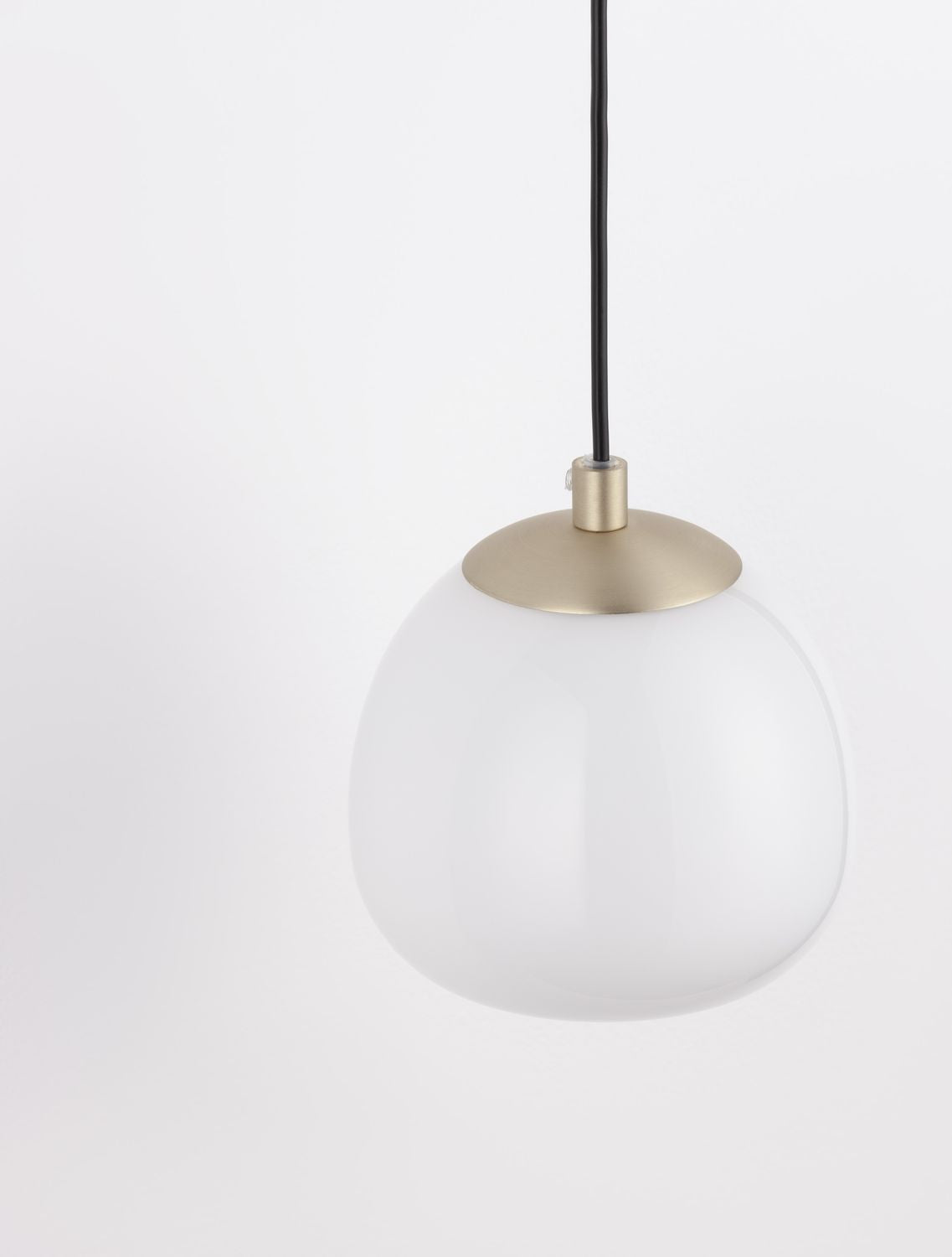 Gros plan du globe de verre opalin et de la bague en laiton doré