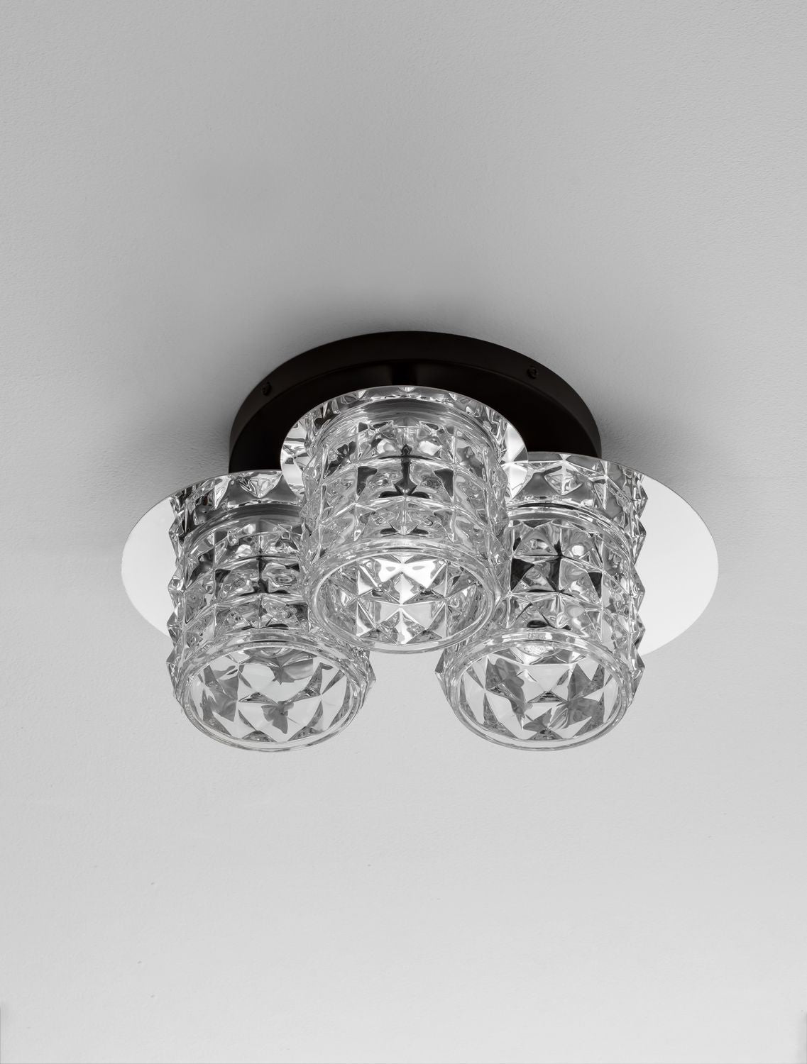 Plafonnier fixé au plafond sur fond gris clair, trois diffuseurs cristal
