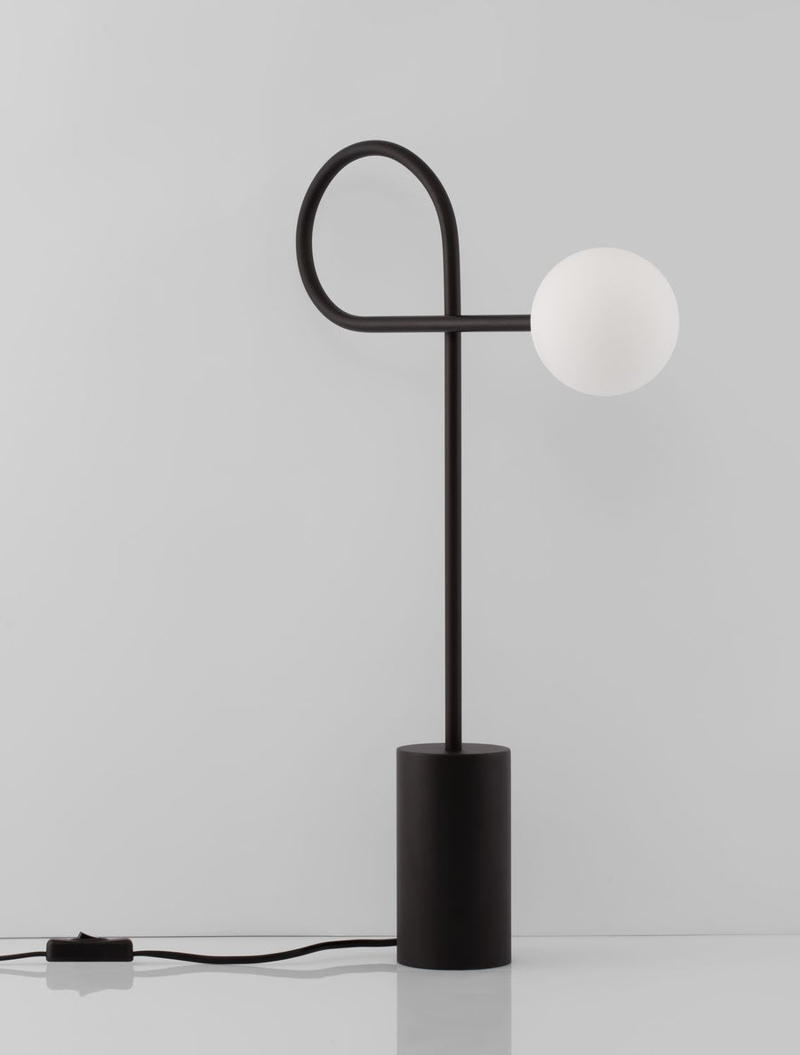 Silhouette de la lampe éteinte, socle cylindrique et tige fine formant boucle