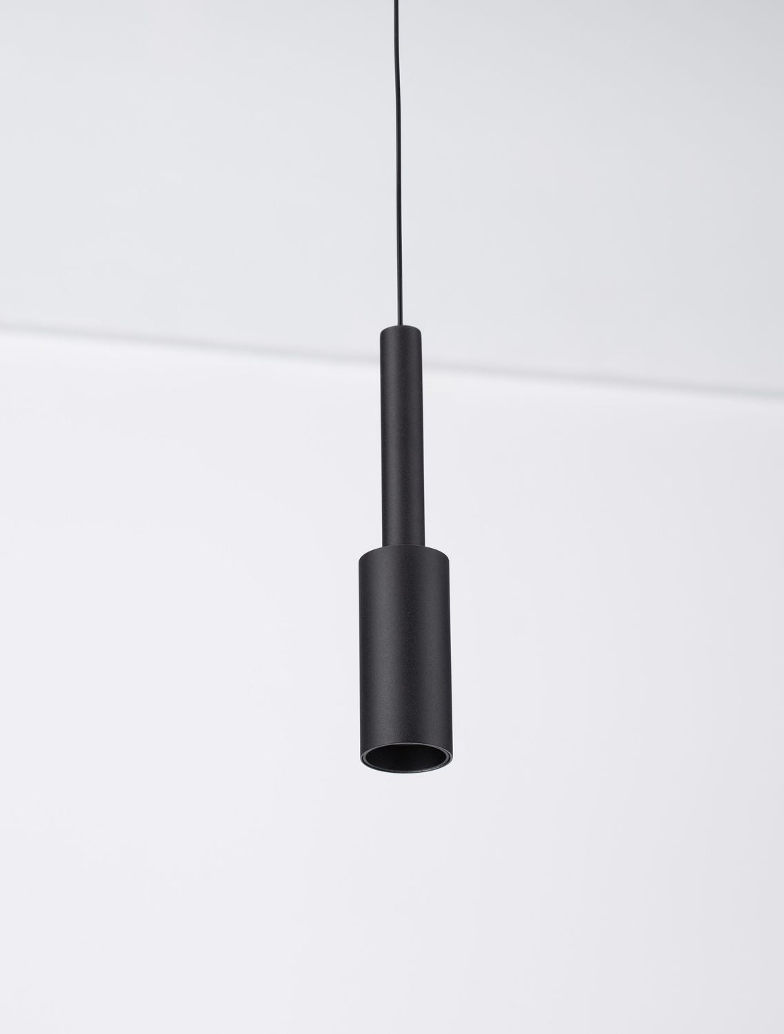 Détail du bas du luminaire montrant l'ouverture cylindrique noire et mate