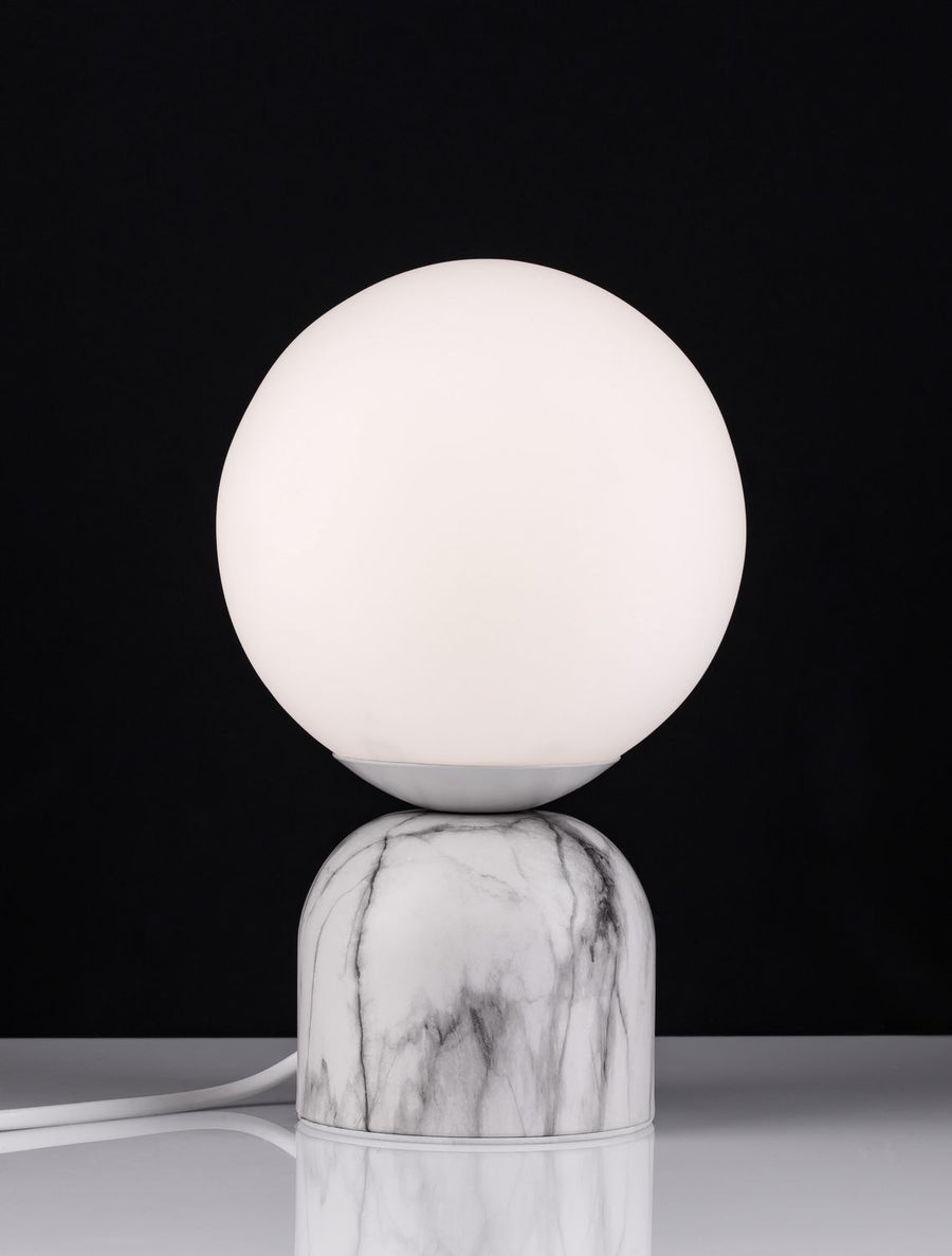 Lampe allumée diffusant une lumière chaude, contraste marqué avec le fond noir.
