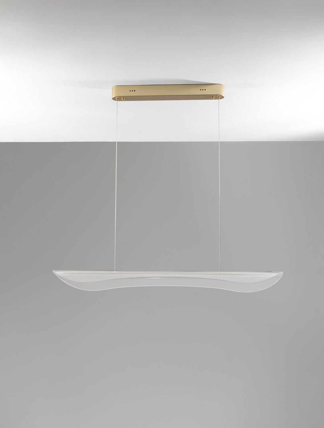 Vue de trois quarts du luminaire allumé sous un plafond gris